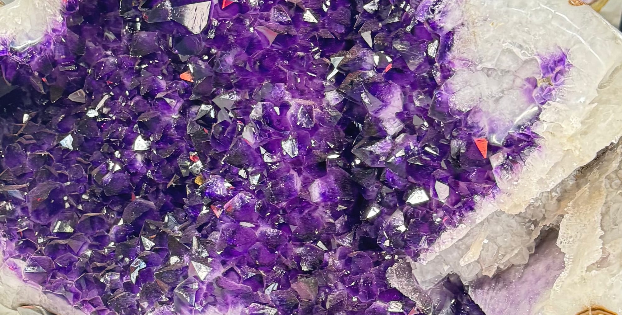 A deeply colored amethyst geode mounted on a metal base in the showroom