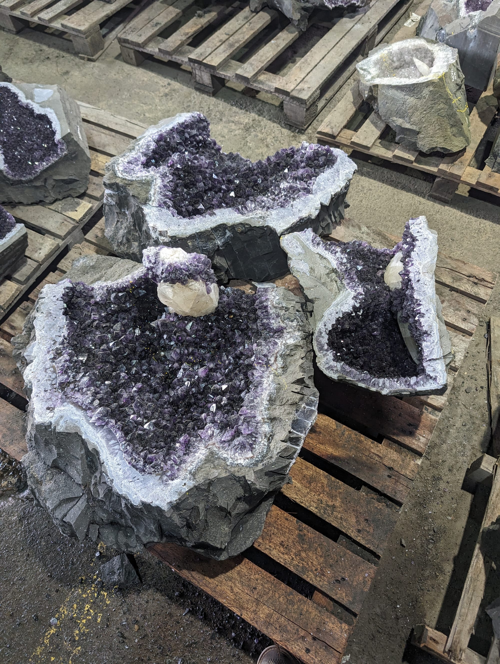 Tres geodas de amatista abiertas, con cristales violetas y borde blanco, sobre una tarima