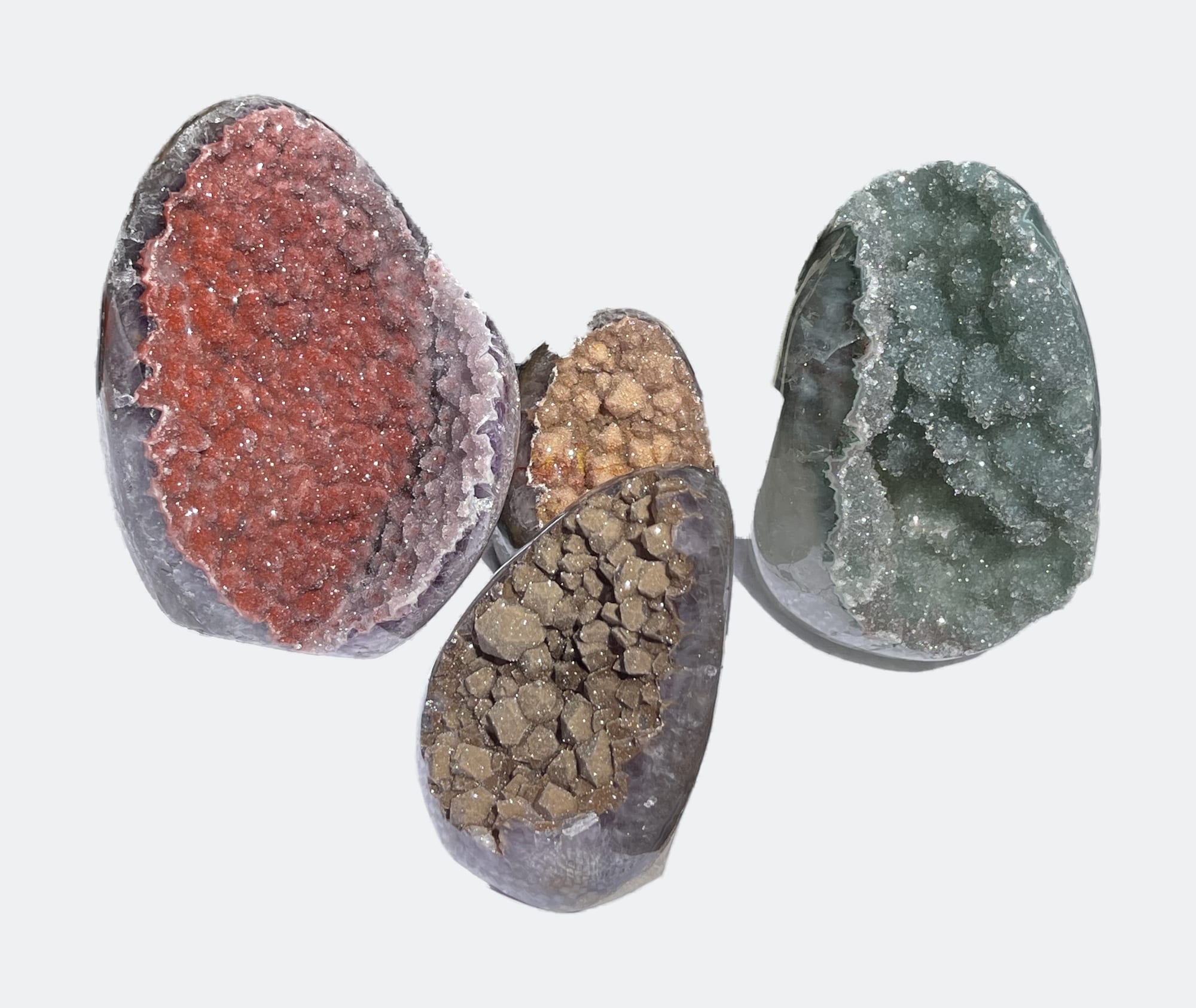Cuatro geodas pulidas con interiores de distinto color: rojo, ocre, marrón y verde