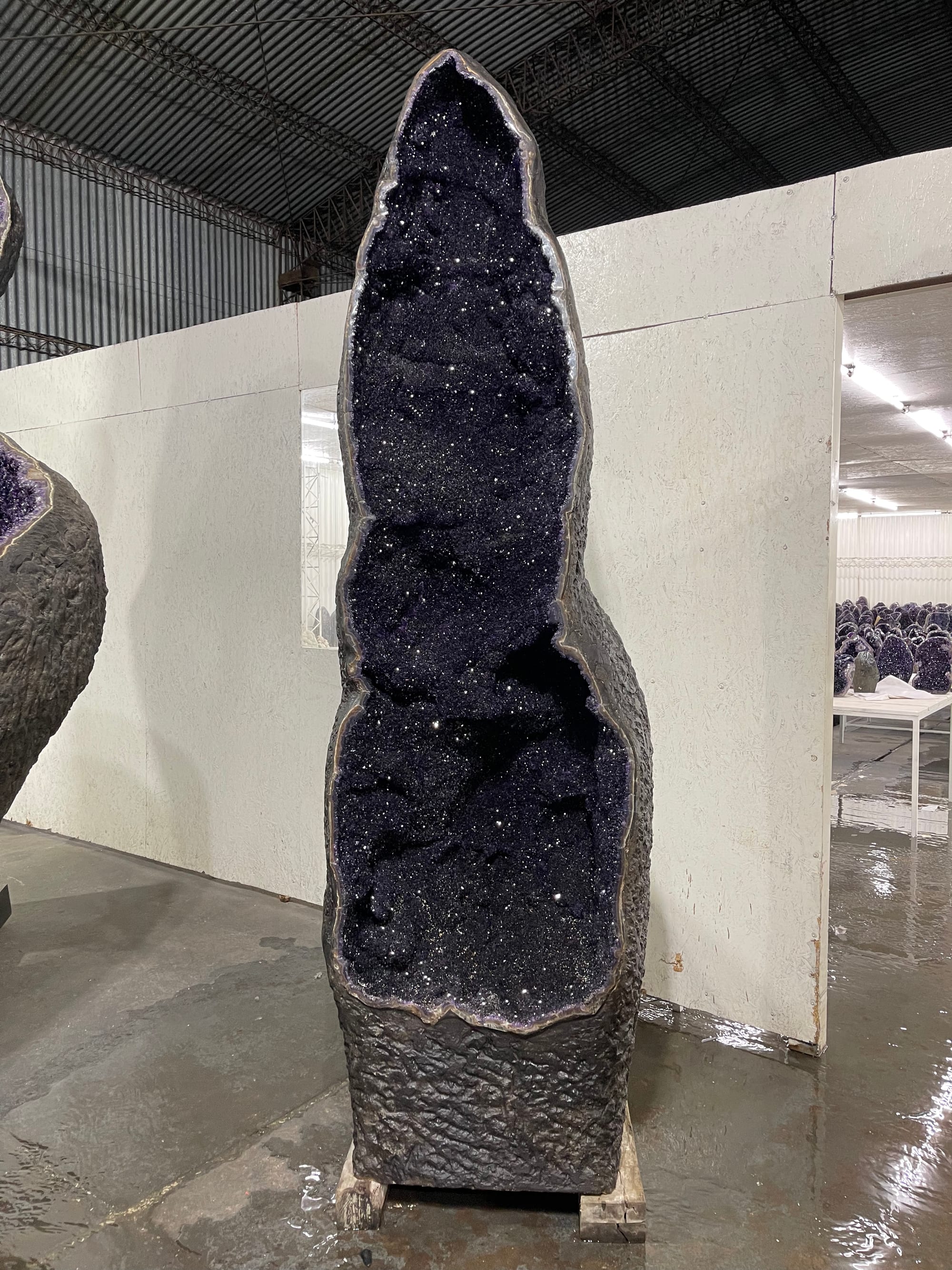 A large-format amethyst geode, standing, several meters tall, in the showroom