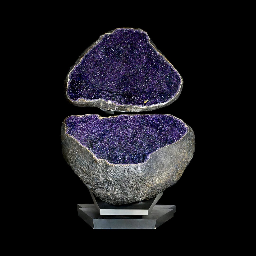 A giant amethyst geode opened into two halves, the top suspended above the base