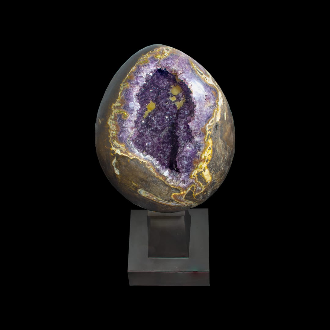An open egg-shaped amethyst geode on a metal stand