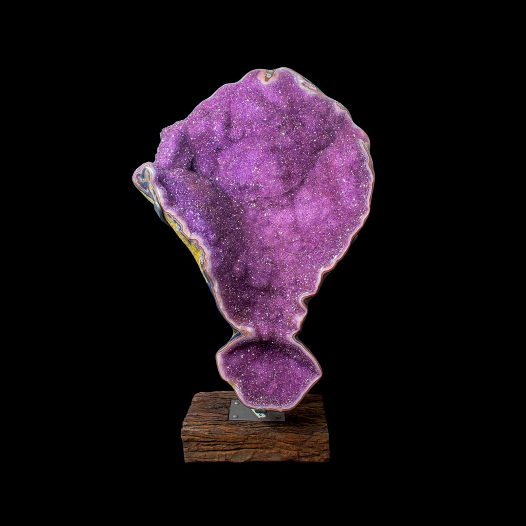 A geode with pink-toned crystals on a wooden base
