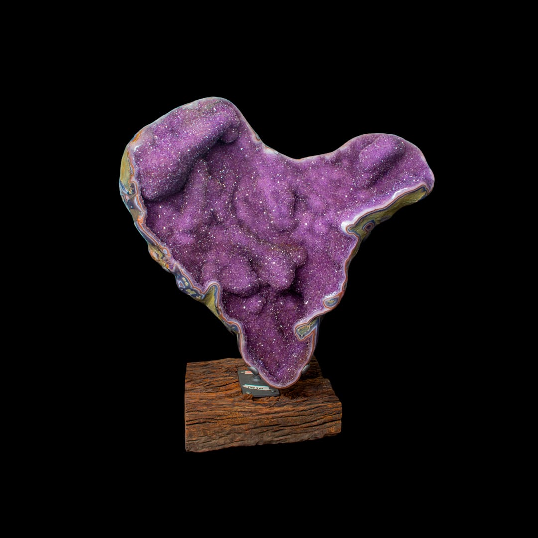 A geode with pink-toned crystals on a wooden base