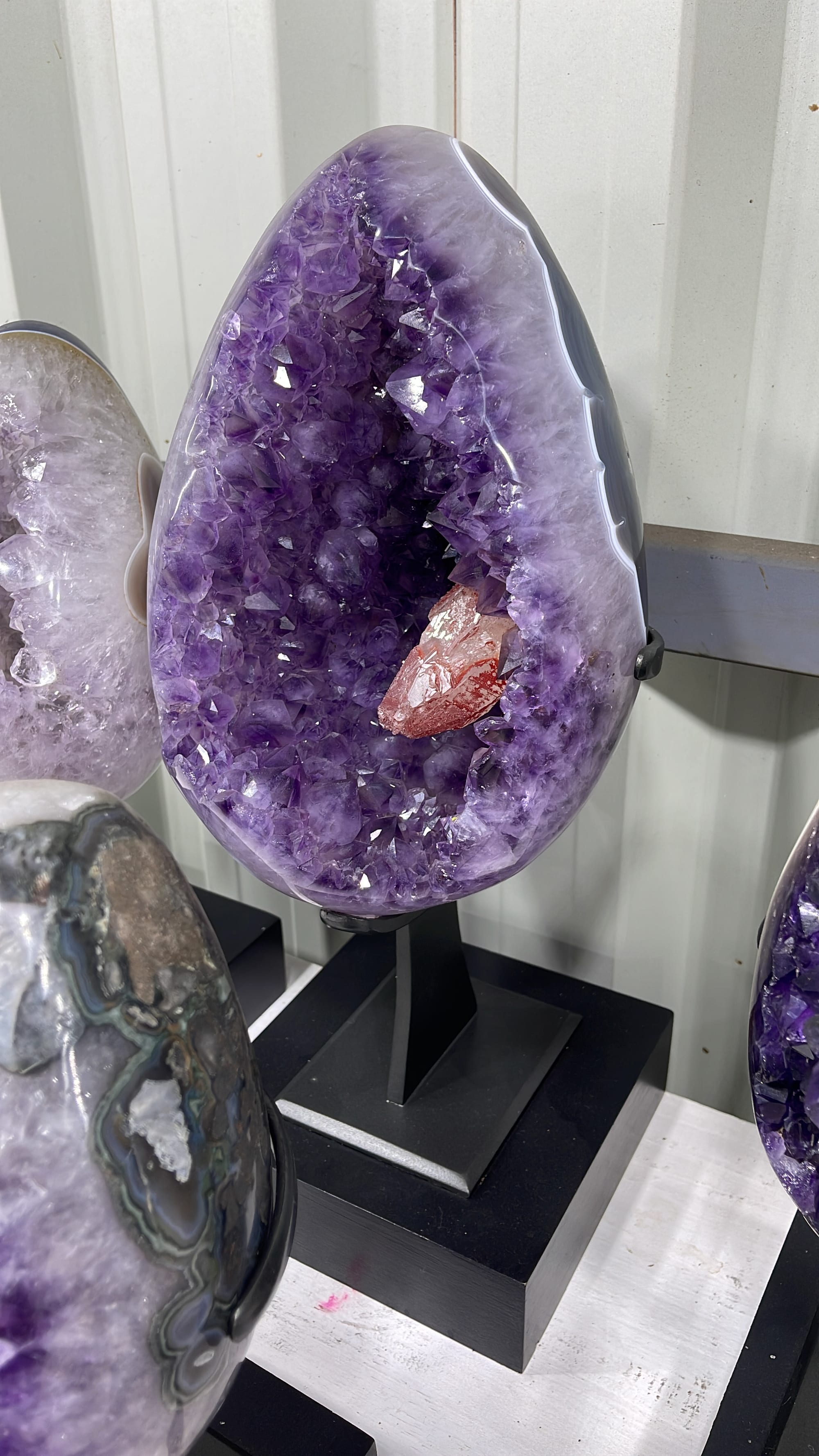A cut and polished amethyst piece with quartz, on a base