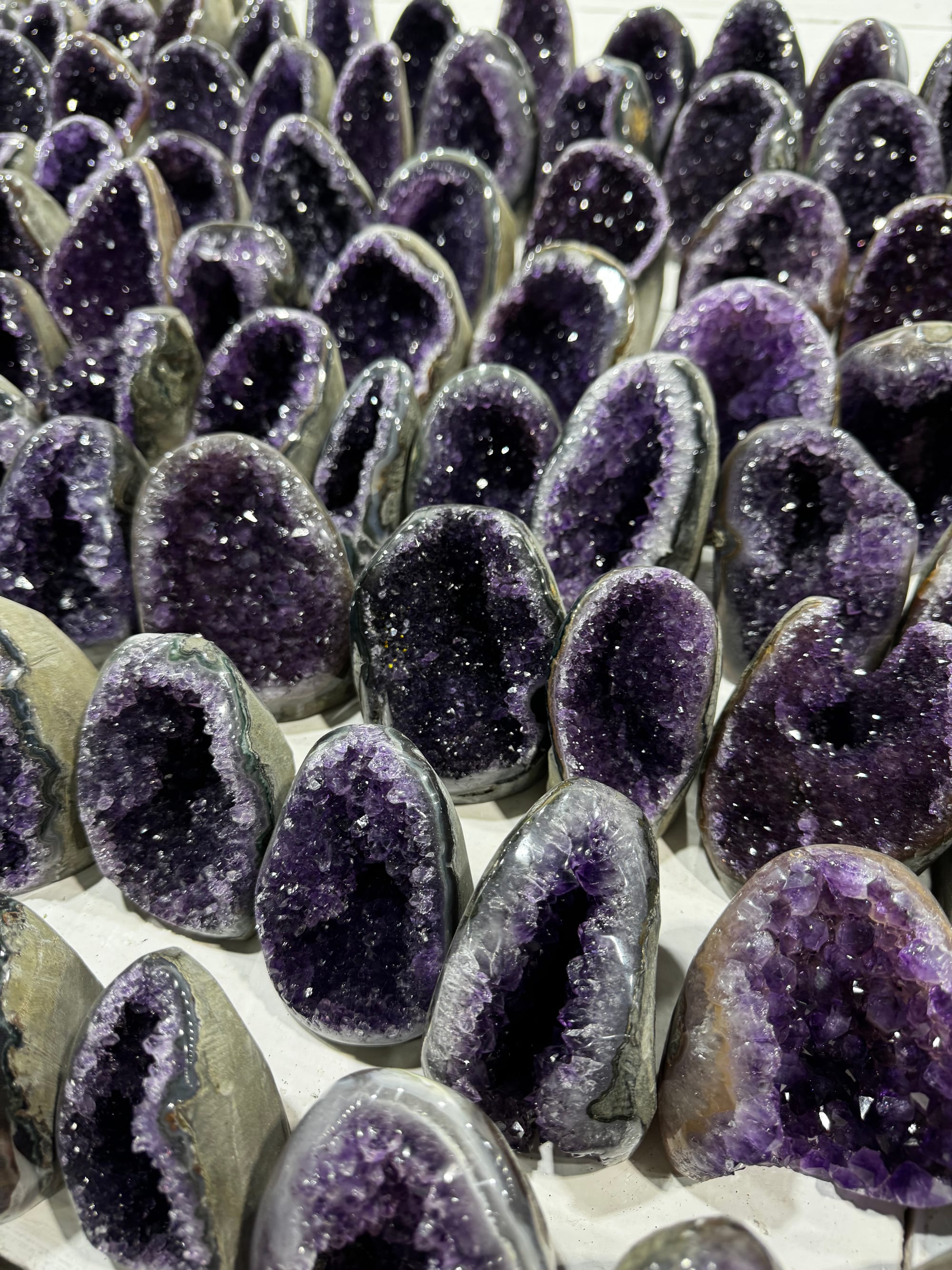 Amethyst geodes standing in rows on a table