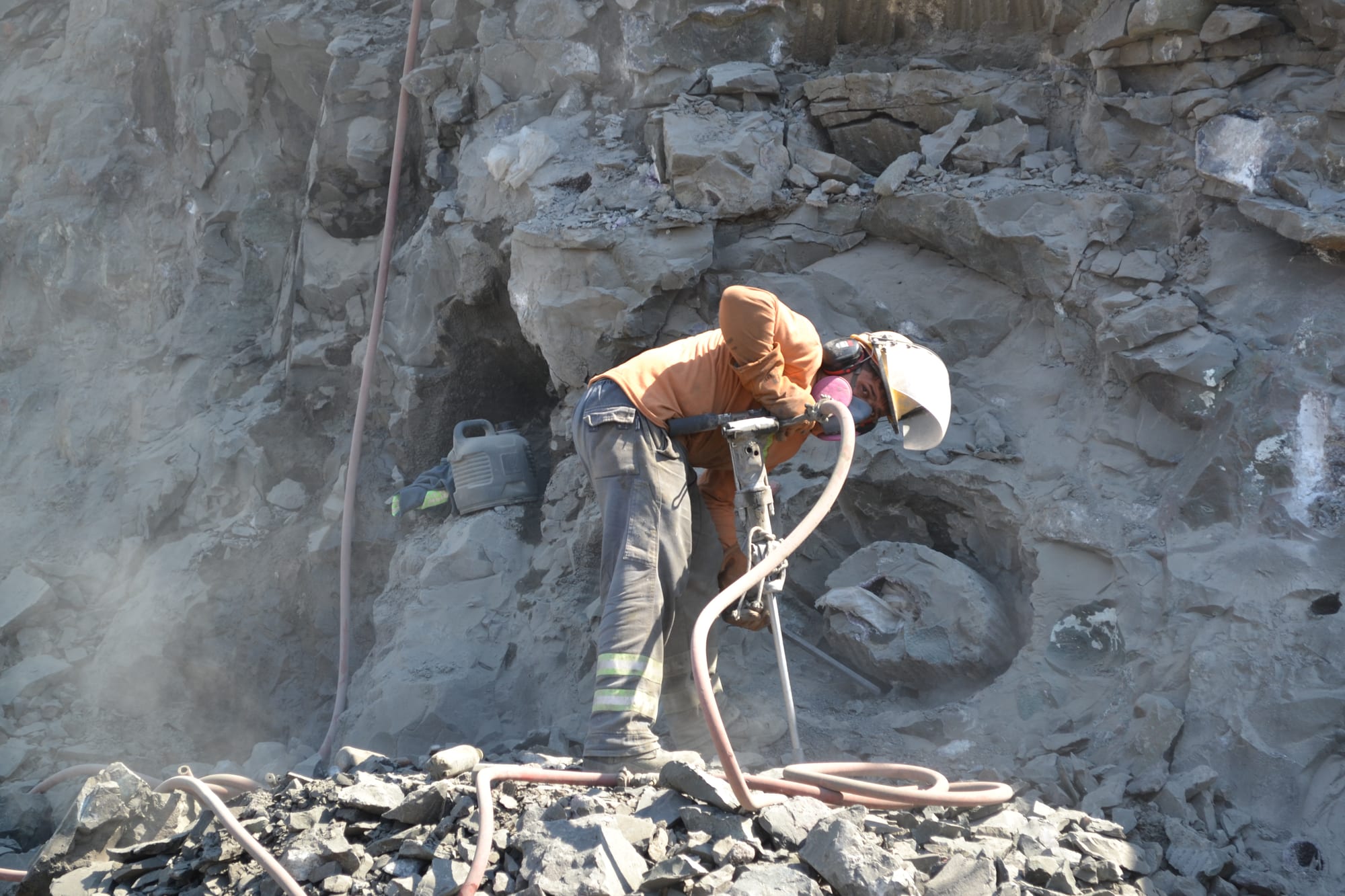 Un cavero con casco trabaja la roca del frente con un martillo neumático, junto a una geoda todavía encastrada