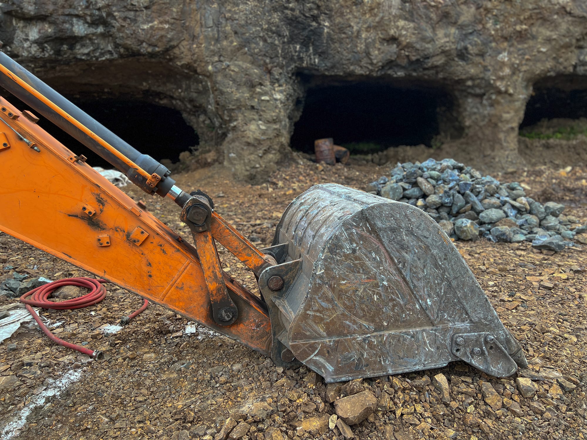 Bocas de galería en el frente de roca, con el balde de una excavadora en primer plano